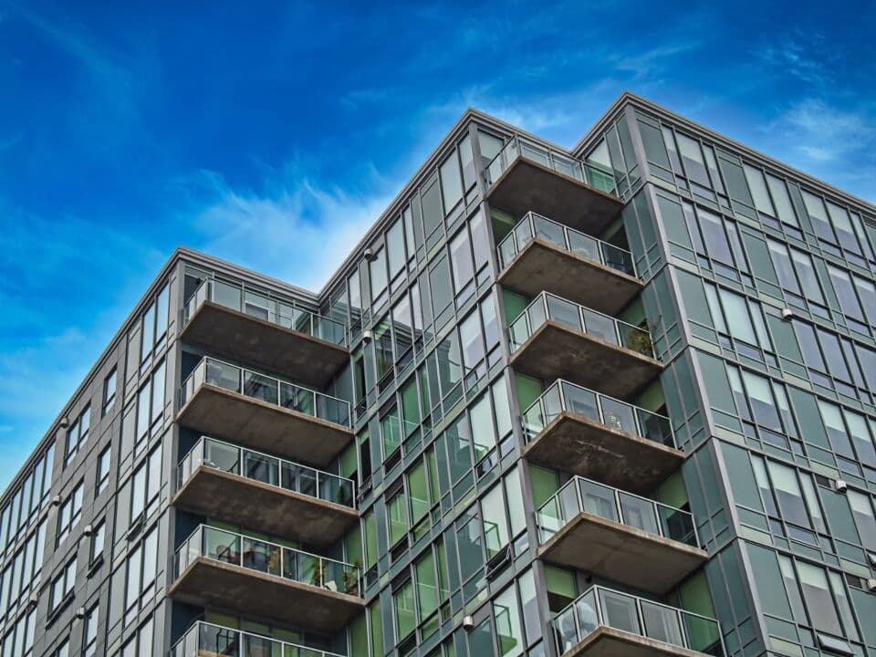 Mid-rise residential building with glass balconies against a blue sky